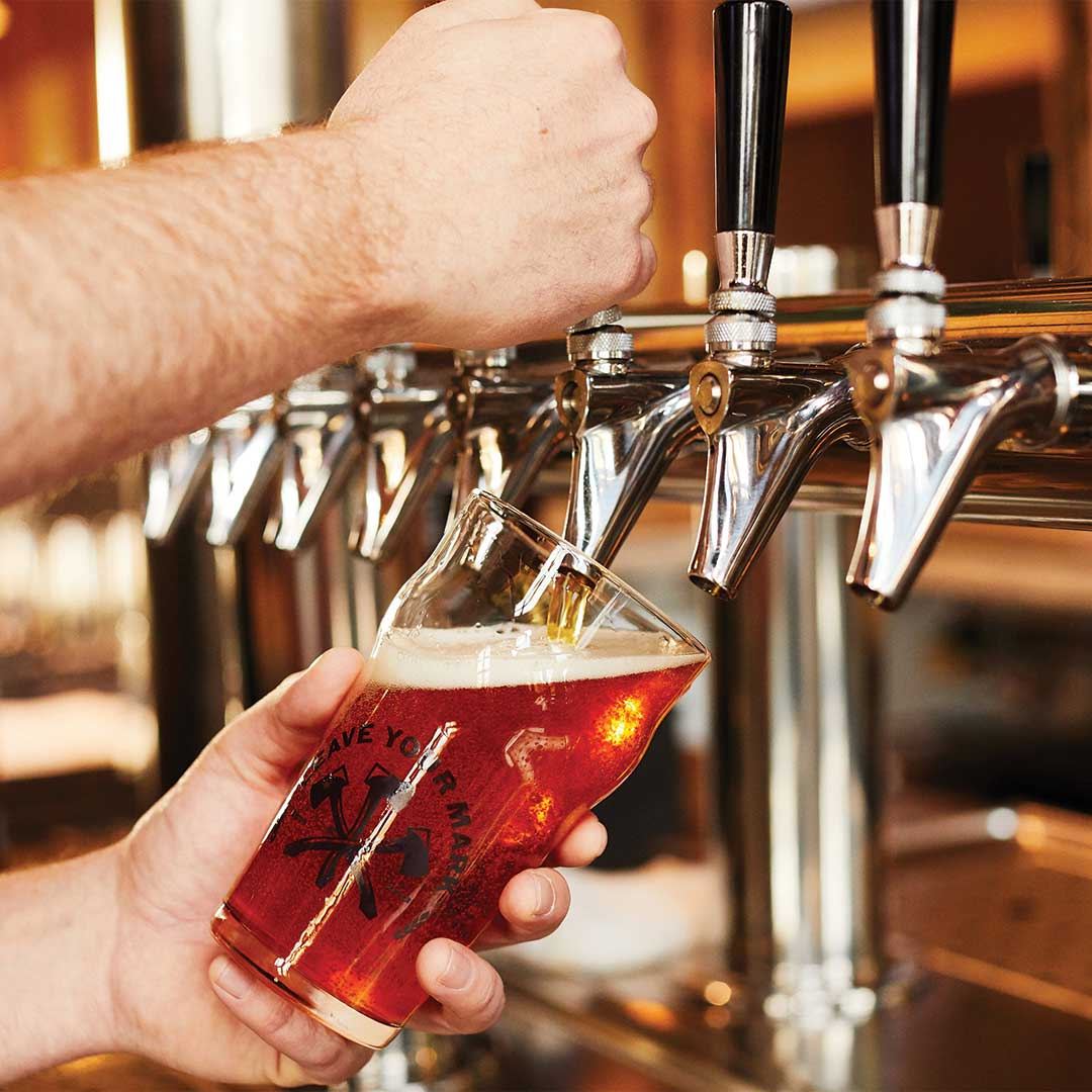 A red-amber beer pouring from the tap into a Three Notch'd glass